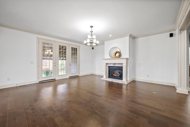 unfurnished living room featuring a chandelier, dark wood-type flooring, a fireplace, baseboards, and crown molding