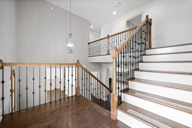 stairs featuring visible vents, a towering ceiling, wood finished floors, a chandelier, and recessed lighting