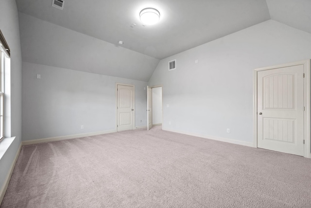 spare room featuring lofted ceiling, light colored carpet, and baseboards