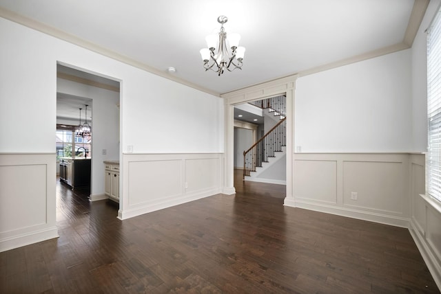 unfurnished dining area with dark wood-style floors, stairway, a decorative wall, and a notable chandelier