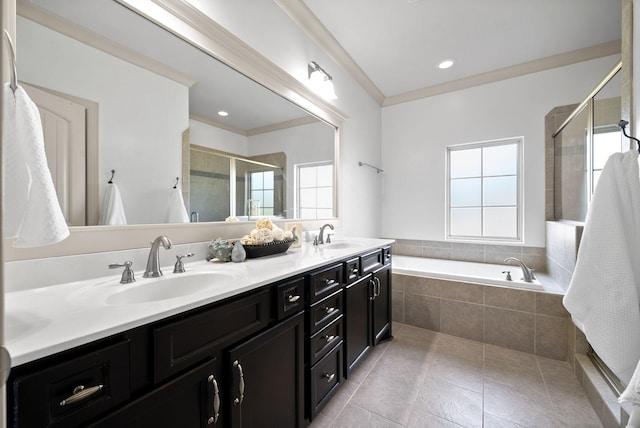 full bathroom featuring a garden tub, double vanity, ornamental molding, a stall shower, and a sink