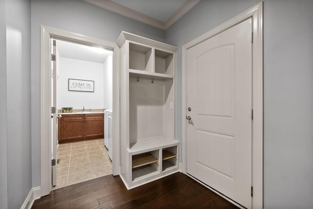 mudroom with a sink, ornamental molding, washer / clothes dryer, and dark wood-type flooring