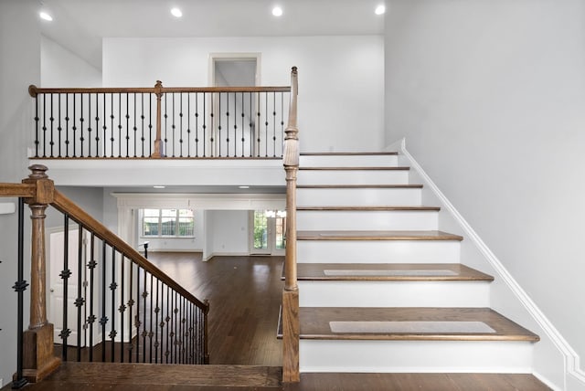 stairs with recessed lighting, a high ceiling, and wood finished floors