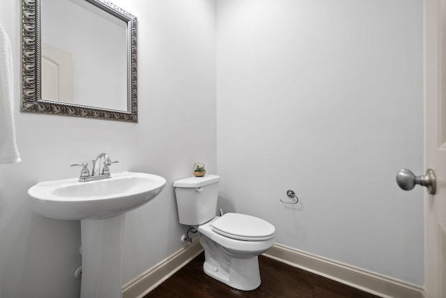 half bath featuring toilet, baseboards, and wood finished floors