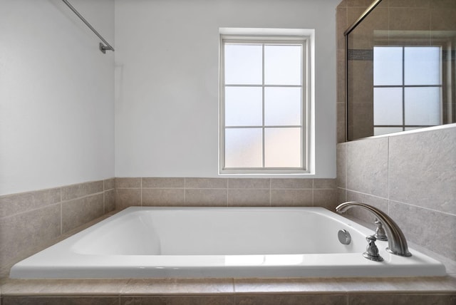 full bathroom featuring a relaxing tiled tub and a wealth of natural light