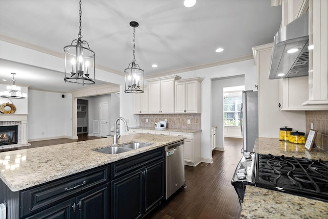 kitchen featuring extractor fan, stainless steel appliances, a sink, dark cabinetry, and a brick fireplace