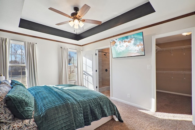 carpeted bedroom featuring a raised ceiling, ensuite bath, a spacious closet, and baseboards