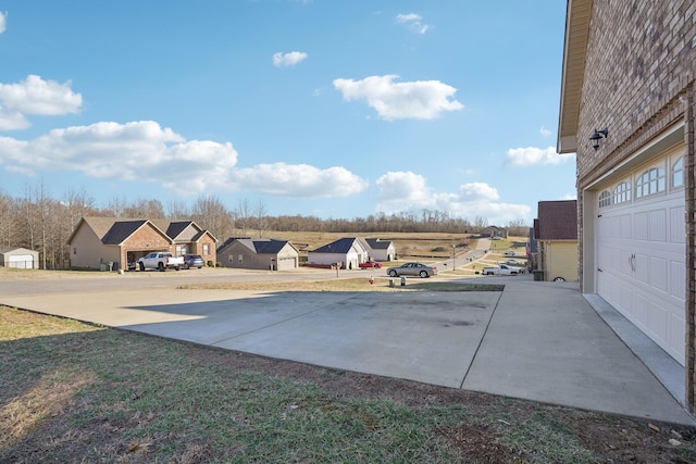 view of yard with a garage, a residential view, and concrete driveway