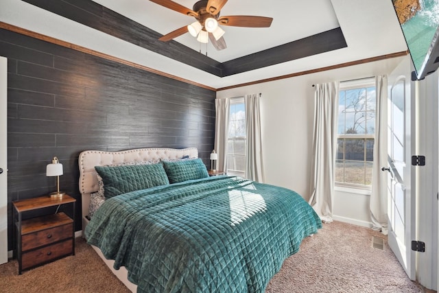 carpeted bedroom featuring a raised ceiling, visible vents, ornamental molding, ceiling fan, and baseboards