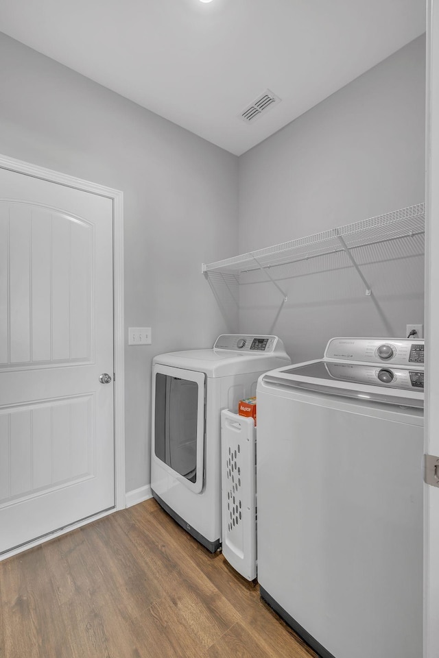 laundry area with laundry area, wood finished floors, visible vents, baseboards, and washer and dryer