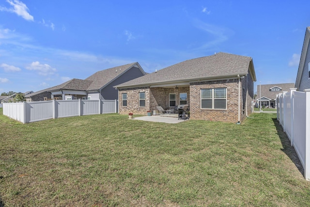 back of house with a yard, brick siding, a patio, and a fenced backyard