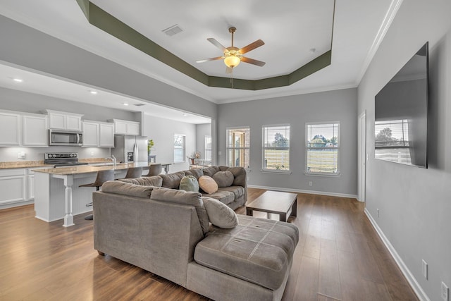 living area with a raised ceiling, visible vents, baseboards, and dark wood-style flooring