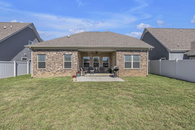 rear view of house featuring brick siding, a fenced backyard, a lawn, and a patio