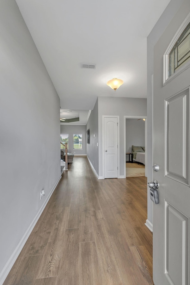 foyer entrance featuring wood finished floors, visible vents, and baseboards