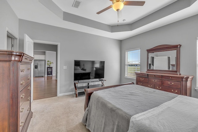 carpeted bedroom featuring stainless steel fridge, baseboards, visible vents, a ceiling fan, and a tray ceiling