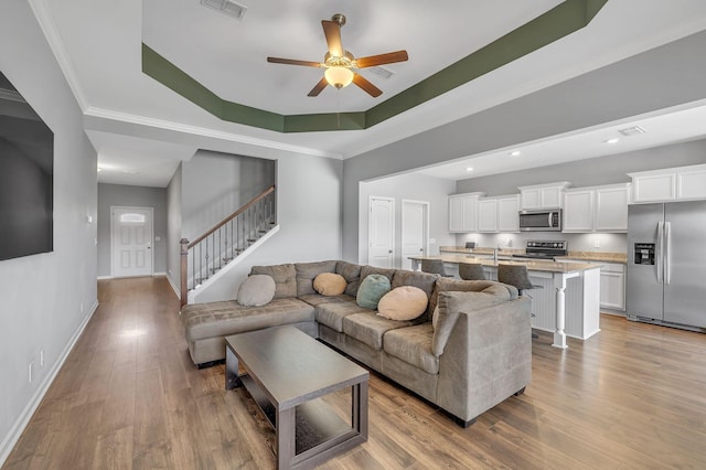 living room with baseboards, a raised ceiling, ceiling fan, stairway, and wood finished floors