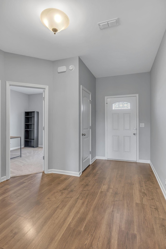 foyer featuring visible vents, baseboards, and wood finished floors