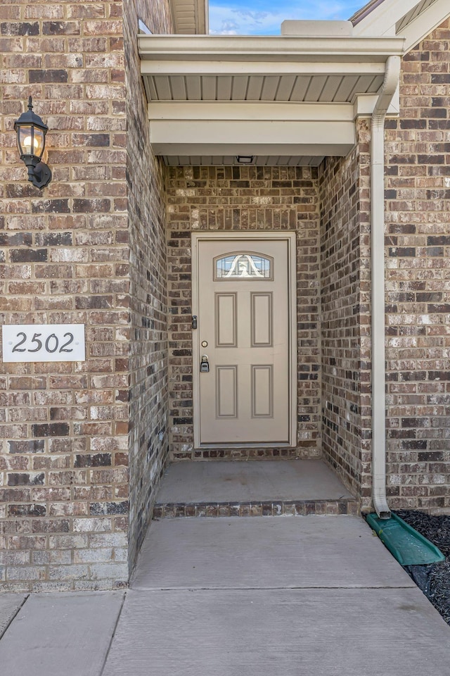 view of exterior entry featuring brick siding