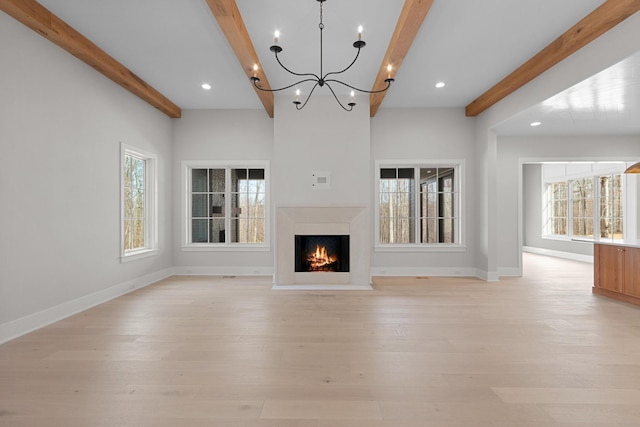 unfurnished living room with beam ceiling, a healthy amount of sunlight, and light wood-style flooring