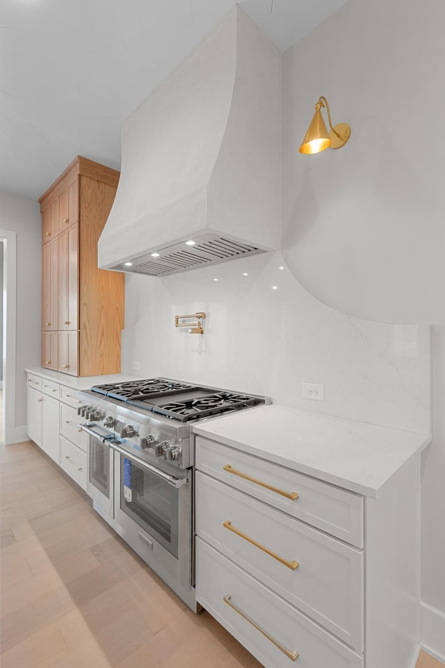 kitchen featuring premium range hood, double oven range, light wood-style floors, white cabinets, and light countertops