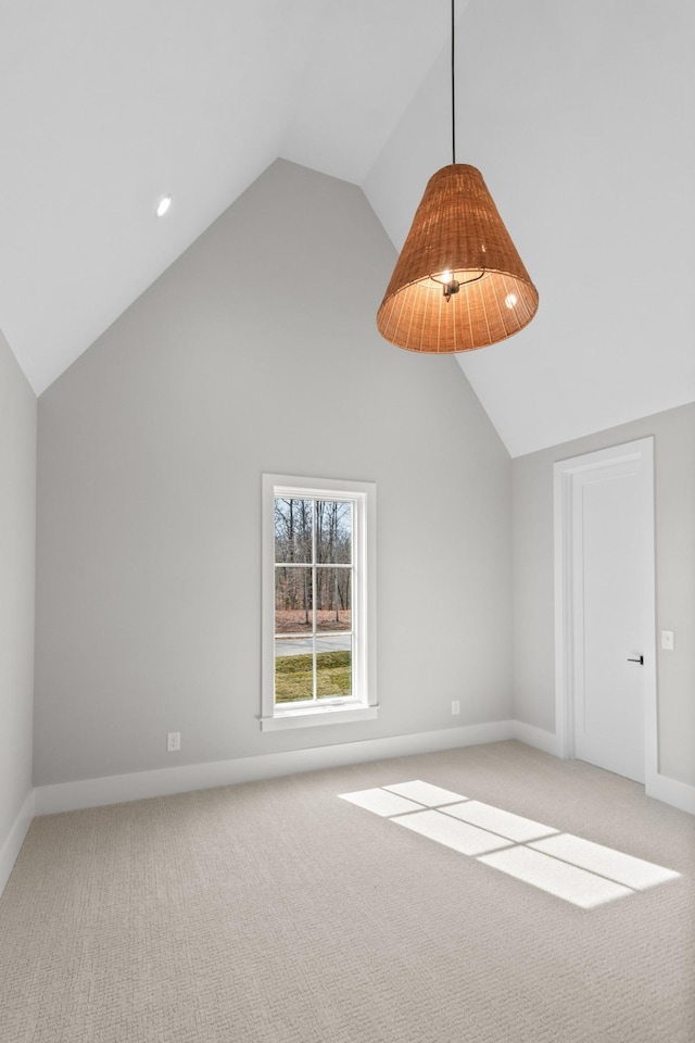 additional living space featuring high vaulted ceiling, baseboards, and light carpet