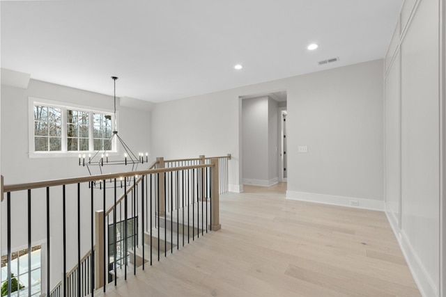 hall featuring light wood-type flooring, an upstairs landing, a notable chandelier, visible vents, and recessed lighting