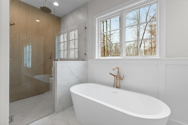 bathroom with a wainscoted wall, a soaking tub, a stall shower, a decorative wall, and marble finish floor