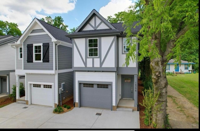 tudor home with a garage, driveway, and roof with shingles