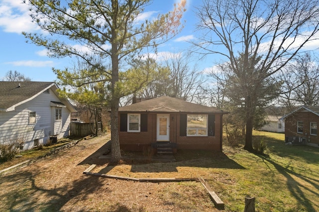 view of front of home featuring central AC, brick siding, and a front lawn