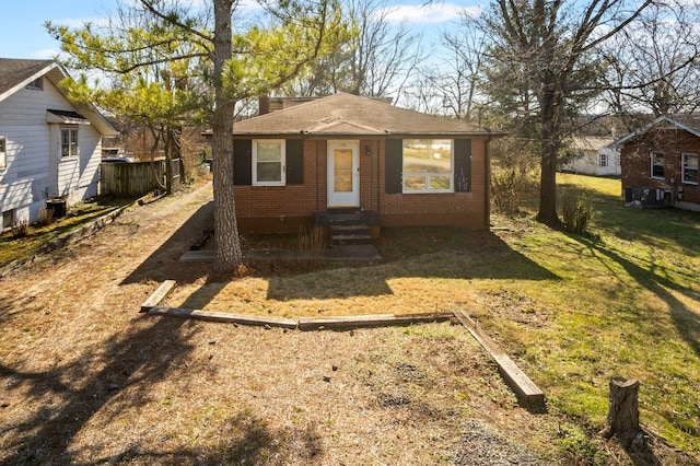 bungalow-style house featuring entry steps, brick siding, a front lawn, and central AC unit