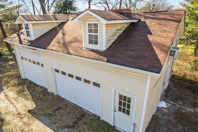 view of home's exterior featuring a garage and roof with shingles