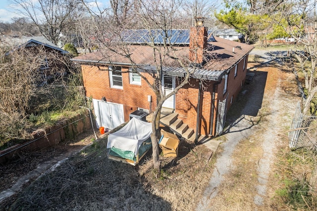 rear view of house with solar panels and brick siding