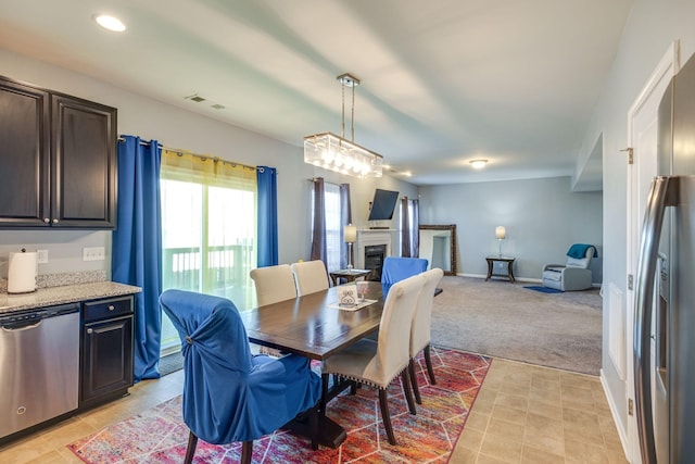 dining space with recessed lighting, light colored carpet, visible vents, a glass covered fireplace, and baseboards