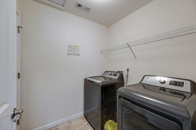 laundry area featuring tile patterned flooring, washing machine and dryer, laundry area, visible vents, and baseboards