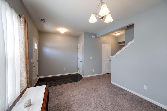 foyer featuring a chandelier, visible vents, baseboards, stairs, and dark carpet