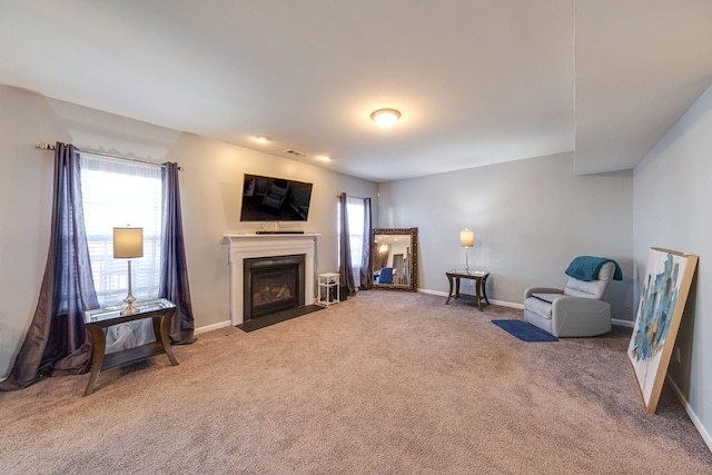 sitting room with a fireplace with flush hearth, carpet, visible vents, and baseboards