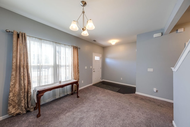 entrance foyer with baseboards, dark carpet, and a notable chandelier