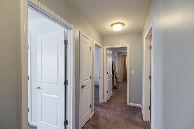 corridor with dark colored carpet and baseboards