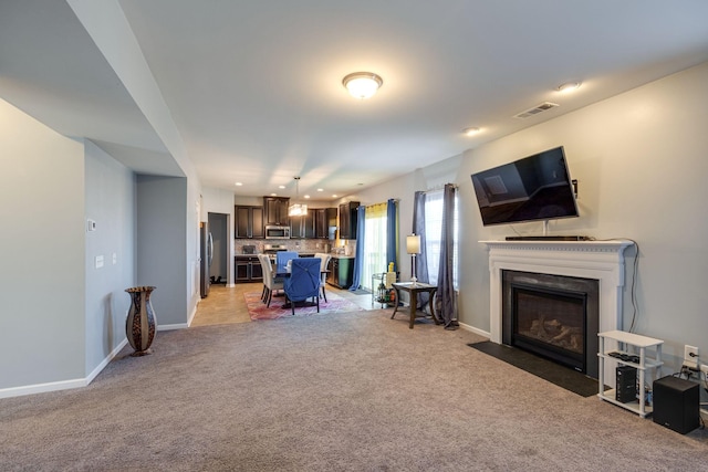 living room with a fireplace with flush hearth, light colored carpet, visible vents, and baseboards