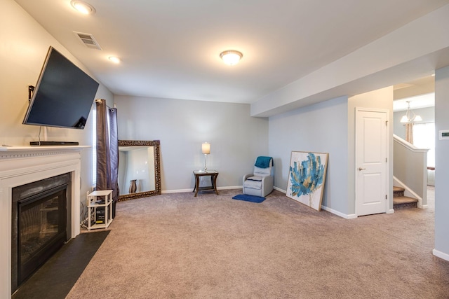 living area with baseboards, visible vents, a glass covered fireplace, stairway, and carpet floors