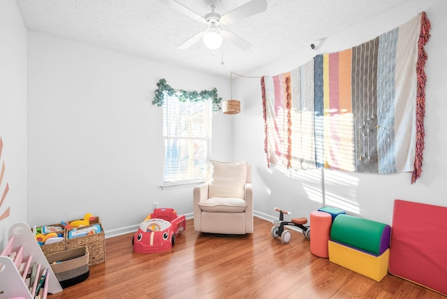 game room with a textured ceiling, baseboards, and wood finished floors