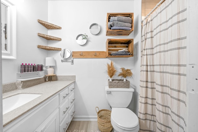 bathroom with toilet, a shower with shower curtain, vanity, and baseboards