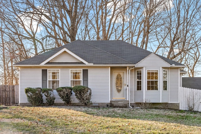 ranch-style home with entry steps, a shingled roof, a front yard, and fence