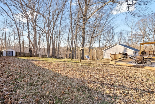 view of yard featuring an outdoor structure, a deck, and a storage shed