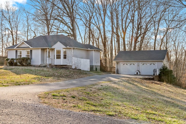 single story home with an outbuilding, a front yard, fence, and a garage