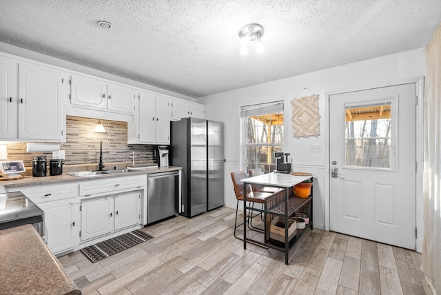 kitchen featuring stainless steel appliances, plenty of natural light, a sink, and light wood-style flooring