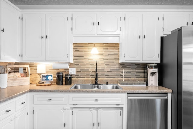 kitchen with tasteful backsplash, appliances with stainless steel finishes, a sink, and white cabinets