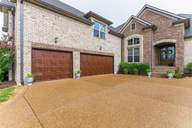 view of front of home featuring french doors, brick siding, driveway, and roof with shingles