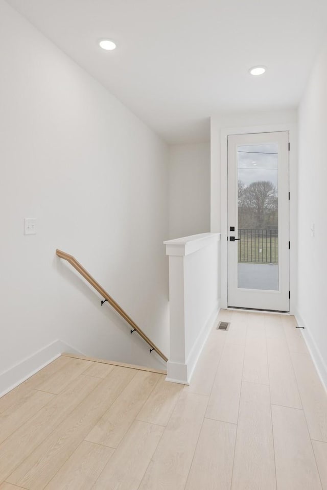 doorway featuring baseboards, wood finished floors, and recessed lighting