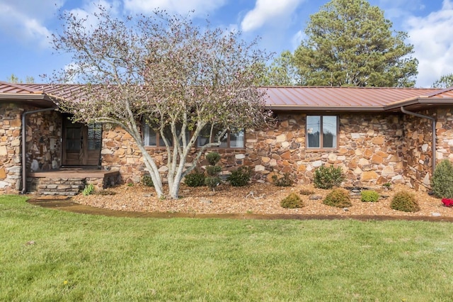 view of side of home with stone siding, metal roof, and a yard